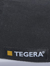 Svart material med litet etikett som har texten "TEGERA" och en gul kvadrat bredvid.
