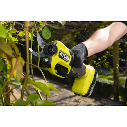 Person använder grön RYOBI-beskärningstång för att klippa grenar i trädgård.