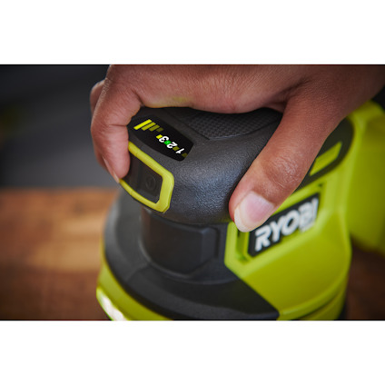 Närbild av en hand som håller i en excenterslip av märket Ryobi med texten "1,2-3 mm" synlig ovanpå.