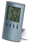 Digital termometer med silverfärgad ram, visar inomhus- och utomhustemperaturer. Svart display med knappar under.