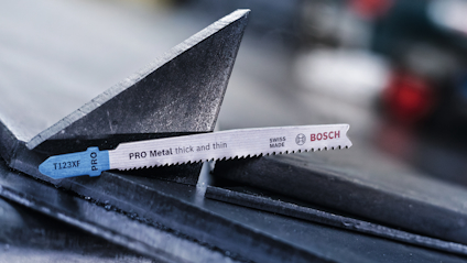 Sågblad av märket Bosch med texten "T123X PF PRO Metal thick and thin SWISS MADE" placerat mot triangulärt metallstycke.
