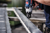 Man använder en Bosch-borrmaskin för att borra i en metallbalk.